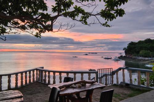 a wooden bench sitting next to a body of water at Pilar Pilapil Beach House in Malapascua in Daanbantayan
