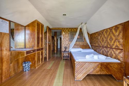 a bed in a room with wooden walls at Pilar Pilapil Beach House in Malapascua in Daanbantayan