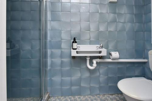 a blue tiled bathroom with a sink and a toilet at Balmoral Waterfront Escape at Lake Macquarie in Balmoral