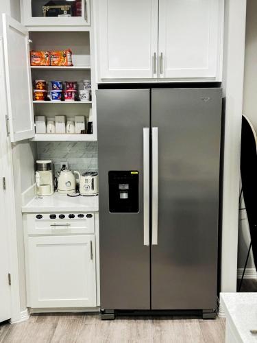 a stainless steel refrigerator in a kitchen with white cabinets at Premier Luxe Villa in Weslaco