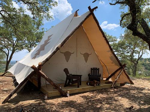 Zelt mit einem Stuhl, einem Tisch und einem Stuhl in der Unterkunft Talula Mesa Glamping Resort - Austin Hill Country in Marble Falls