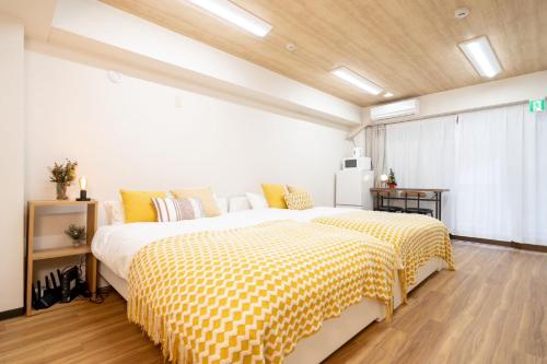 a bedroom with a large bed with yellow and white sheets at Tookin house 池袋 in Tokyo