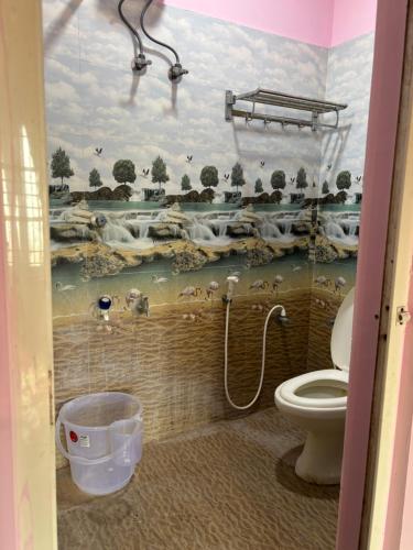 a bathroom with a toilet and a mural of animals at Usha Nest Home Stay in Madurai