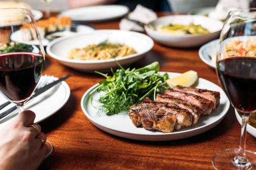a table with plates of food and glasses of wine at Hotel TOTTO Wollongong in Wollongong