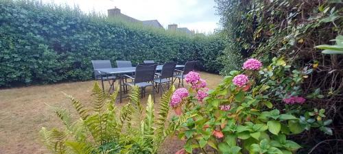 a table and chairs in a garden with flowers at Charmante maison de pêcheur in Carantec
