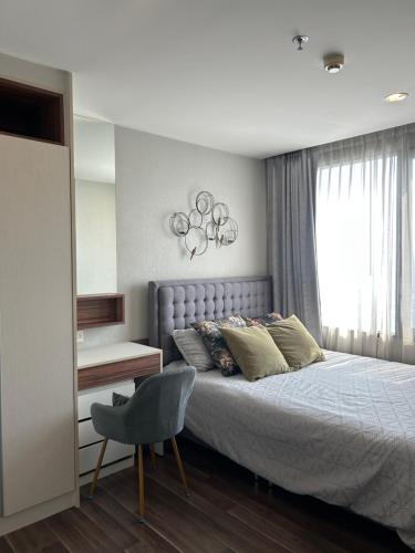 a bedroom with a bed and a chair and a window at BTS Bearing 23Fl 68sqm condo with open city view Shared rooftop and gym in Samut Prakan