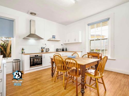 a kitchen and dining room with a wooden table and chairs at Summer Lodge-Esplanade frontage Character & charm in Victor Harbor