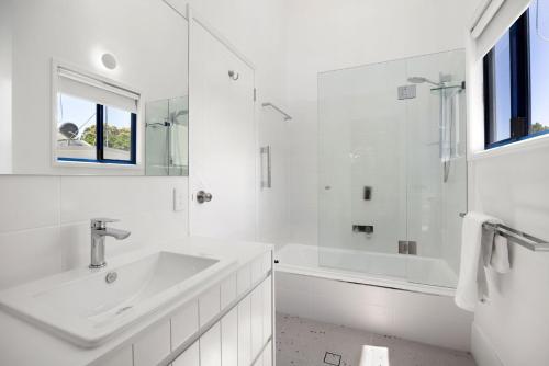 a white bathroom with a sink and a tub at Unit 3 Kookaburra Lodge 8 Little Cove Road Little Cove in Noosa Heads