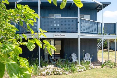 a blue house with two white chairs on the porch at The Blue Bunyip - 3 Bunyip St in Goolwa South