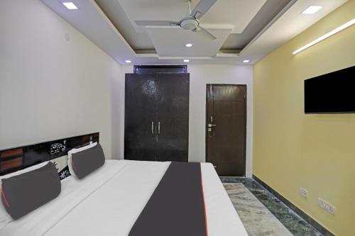 a room with a bed and a tv and a door at Hotel N R Prime Royalty Greater Kailash - Couple Friendly in New Delhi