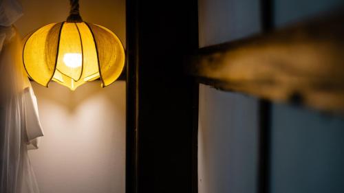 a light hanging from a wall next to a window at Khmer Lodge - Eco-Lodge in Phumĭ Réach Born