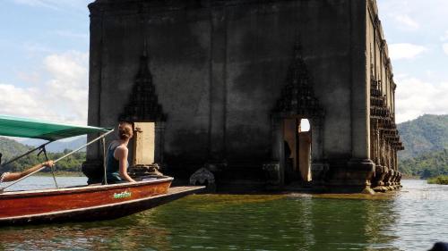 a woman in a boat on the water near a bridge at Baan Job Sangkhlaburi in Sangkhla Buri