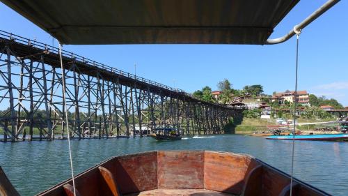 a boat in the water next to a bridge at Baan Job Sangkhlaburi in Sangkhla Buri