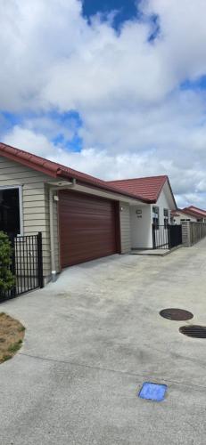 a house with a garage with a red roof at 3 Bedroom home in Palmerston North with BBQ and Sky Tv in Palmerston North