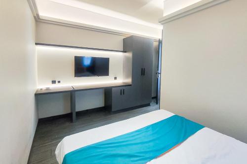 a room with a bed and a desk with a tv at Sans Hotel Bogor in Bogor