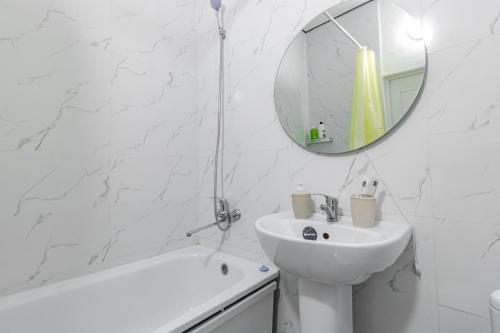 a white bathroom with a sink and a mirror at Красотка на Нурлы Жол in Astana