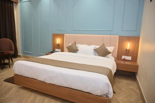 a bedroom with a large bed with white sheets at Arunachal Bhawan in Tinsukia