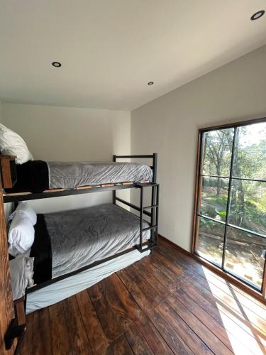 a bedroom with two bunk beds and a window at Cabañas Corazón del Bosque in Tapalpa