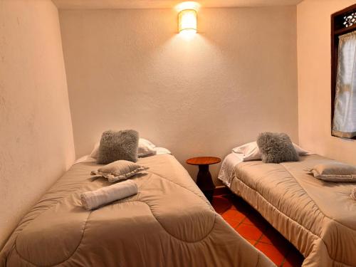 a room with two beds and a table in it at Casa Xiscua in Villa de Leyva