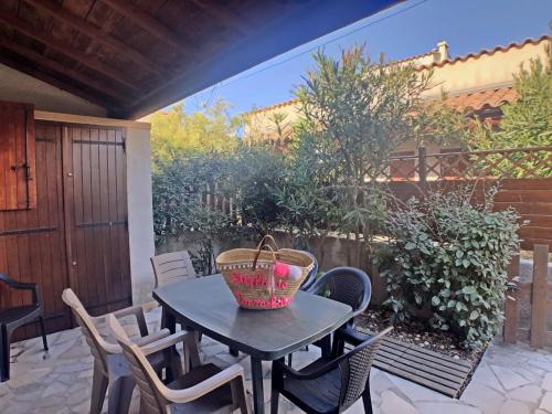- une table de patio avec des chaises et un panier dans l'établissement Appartement pour 6 pers. avec piscine, proche mer - FR-1-475-208, à Saintes-Maries-de-la-Mer