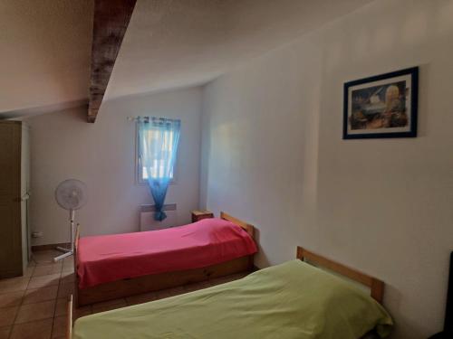 - une chambre avec 2 lits, une fenêtre et un ventilateur dans l'établissement Appartement pour 6 pers. avec piscine, proche mer - FR-1-475-208, à Saintes-Maries-de-la-Mer