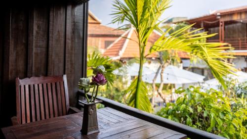 a flower in a vase on a table on a porch at Khmer Lodge - Eco-Lodge in Phumĭ Réach Born