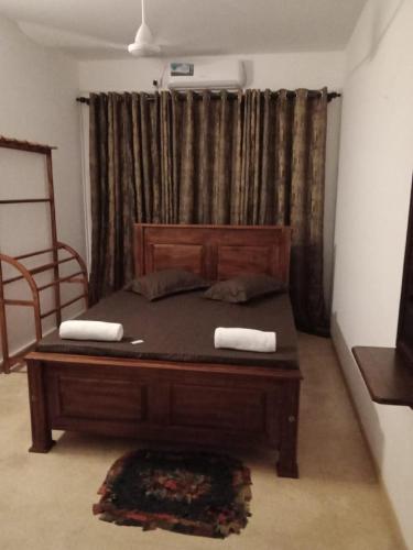 a bedroom with a wooden bed with two towels on it at Grand Villa Wellawatta in Colombo