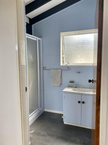 a blue bathroom with a sink and a window at Totara Bach in Tata Beach