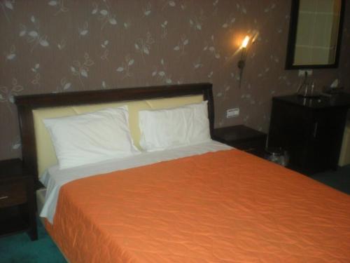 a bedroom with a bed with an orange bedspread at Achillion Palace in Kalambaki