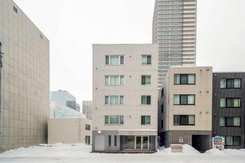 a tall building with snow in front of some buildings at Court Villa Sapporo 403 in Sapporo