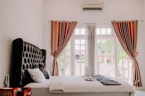 a bedroom with a bed and a large window at Cozy Corner House in Banyuwangi