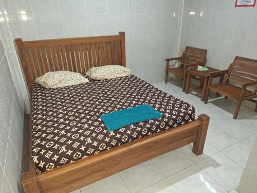 スンギギにあるAnggrek Spa & Homestayのベッドルーム1室(木製ベッド1台、椅子2脚付)