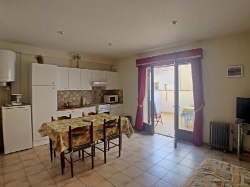 une cuisine avec une table à manger et une cuisine avec une porte dans l'établissement Appartement pour 4 pers. avec cour privative aux Saintes-Maries-de-la-Mer - FR-1-475-210, à Saintes-Maries-de-la-Mer