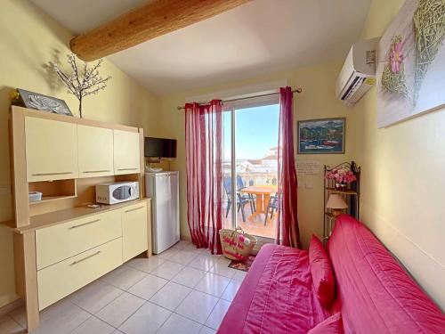 un salon avec un lit rose et une cuisine dans l'établissement Appartement 4 pers avec vue mer, climatisé, aux Saintes-Maries-de-la-Mer - FR-1-475-212, à Saintes-Maries-de-la-Mer