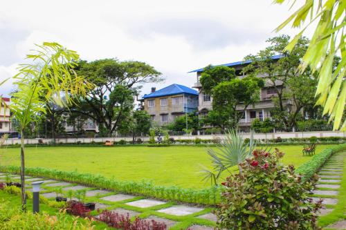 a green park with buildings in the background at Arunachal Bhawan in Tinsukia