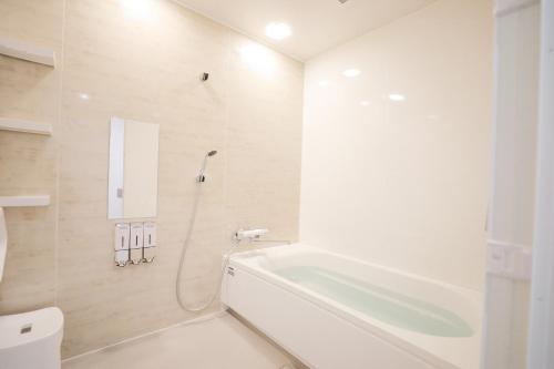 a white bathroom with a tub and a toilet at Kametsu Surf House in Kametsu