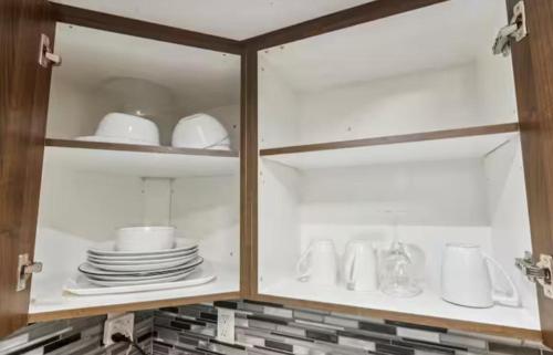 a cabinet with plates and dishes in it at Comfortable & Cozy 2BR Hideaway Basement Appartment in Brampton