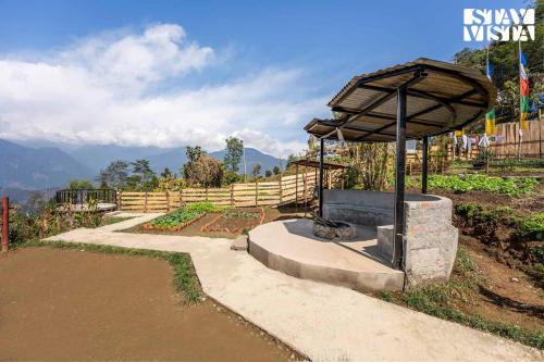 a fountain in a garden with a wooden fence at StayVista at The Stargazer with Mountain Views, Bonfire, Lawn in Pelling