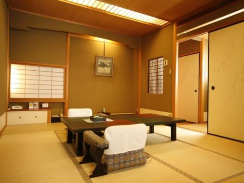 a living room with a table and two chairs at Sennennoyu Koman in Toyooka
