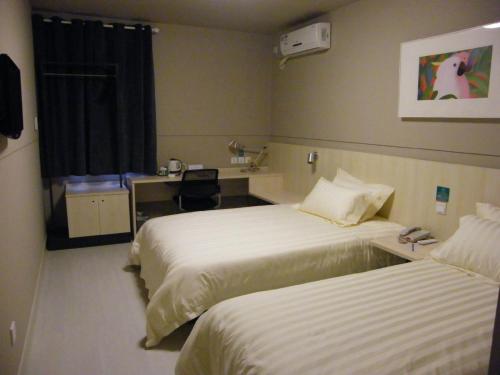 a hotel room with two beds and a desk at Jinjiang Inn Xining Mojia Street Food Street in Xining