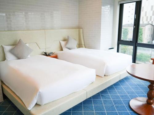 two beds sitting on a bench in a room at Rembrandt Style Yokohama Sakuragicho in Yokohama