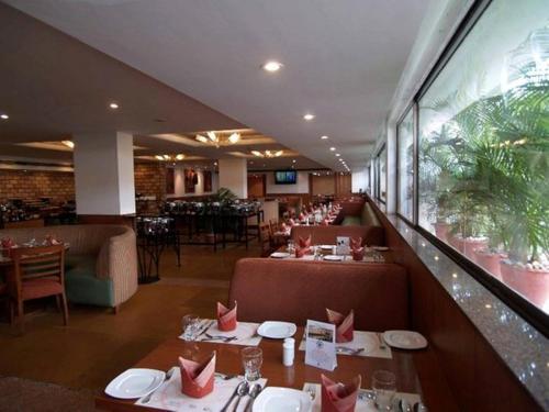 a restaurant with tables and chairs and a large window at Ramada by Wyndham Chennai Egmore in Chennai