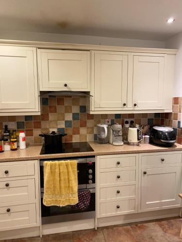 a kitchen with white cabinets and a stove top oven at Bickley London Holiday Home in Bromley