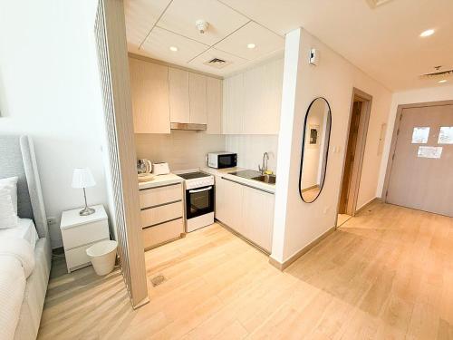 a small kitchen with white cabinets and a mirror at Yas Island Waters Edge Studio by Central Stay in Abu Dhabi