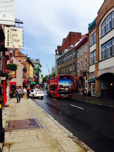 a red bus is driving down a city street at Auberge St-Louis in Quebec City