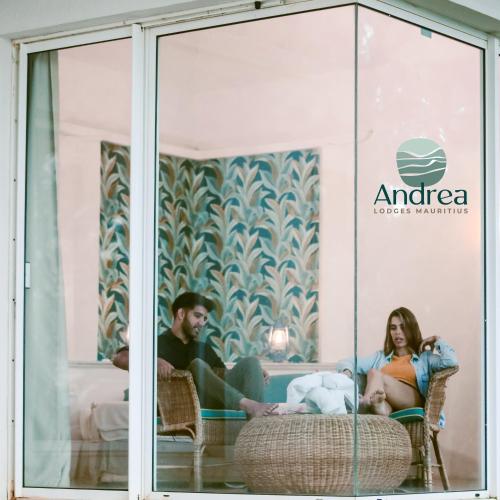 a man and woman sitting in chairs in a window at Andrea Lodges in Souillac