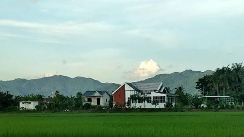 a group of houses next to a green rice field at FarmStay Tawanchai ฟาร์มสุขตะวันฉาย YS in Ban Fak Huai