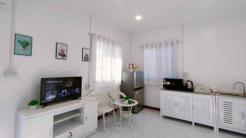 a white living room with a television and a table at FarmStay Tawanchai ฟาร์มสุขตะวันฉาย YS in Ban Fak Huai