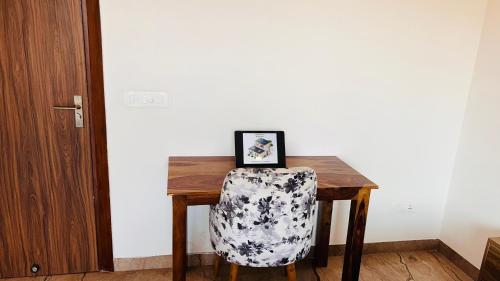 a chair sitting at a wooden table with a picture at Liv Regalia Suites - Medanta Hospital, Sector 39, Gurgaon in Gurgaon