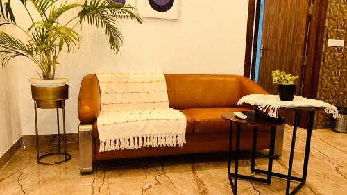 a brown couch sitting in a room with two tables at Liv Regalia Suites - Medanta Hospital, Sector 39, Gurgaon in Gurgaon